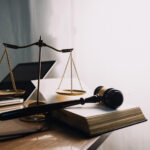 Biurko z wagą sprawiedliwości, młotkiem sędziowskim, książką prawniczą i laptopem – symbol nowoczesnego środowiska pracy prawnika