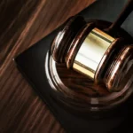 Zbliżenie na drewniany młotek sędziowski spoczywający na podstawce, symbolizujący wymiar sprawiedliwości i autorytet sądowy